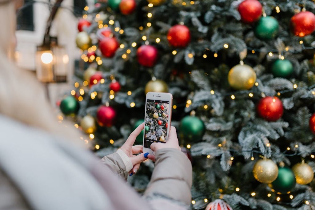 Close-up of a smartphone capturing a decorated Christmas tree with colorful ornaments.